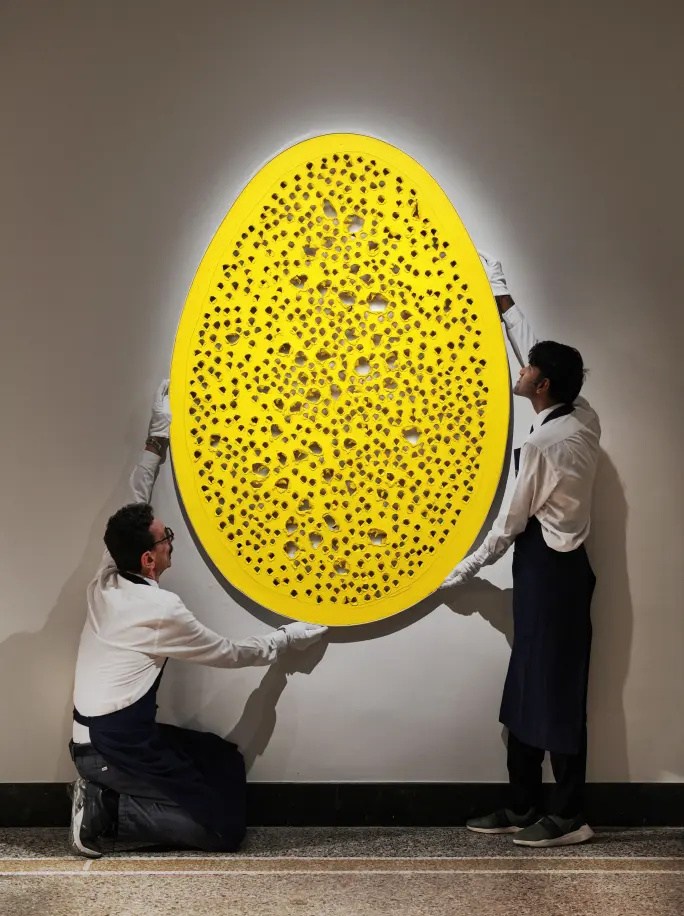 Handlers carrying Lucio Fontana's luminous yellow oval work La fine di Dio